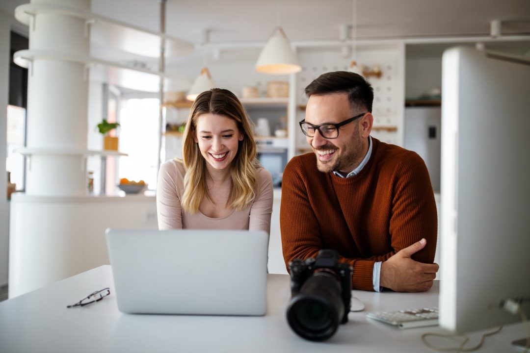 Graphic designers working in office with laptop. Team discussing ideas in advertising agency